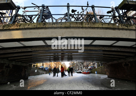 Die Menschen gehen auf zugefrorenen Kanälen im Zentrum von Amsterdam, Niederlande. Stockfoto