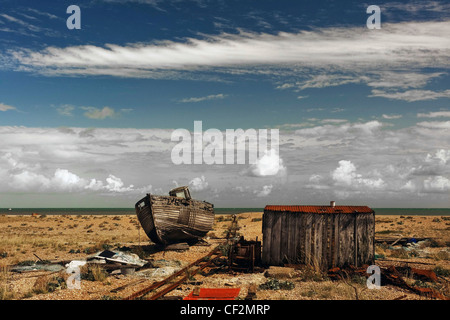 Eine verlassene Holzboot gestrandet neben einer Fishermans Holzhütte auf dem Kiesstrand bei Dungeness. Stockfoto