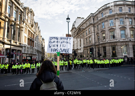 Ein Demonstrant hält ein Plakat vor einer Linie der Metropolitan Police Officers bei einer Demonstration gegen die Regierung educat Stockfoto