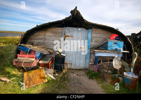 Eine ungewöhnliche Schuppen rund um den Hafen auf der Heiligen Insel, umgebaut aus einem alten Fischerboot Hering. Stockfoto