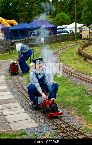 Eine Autofahrerin eine Dampfmaschine auf der Audley End Miniatur-Eisenbahn. Stockfoto