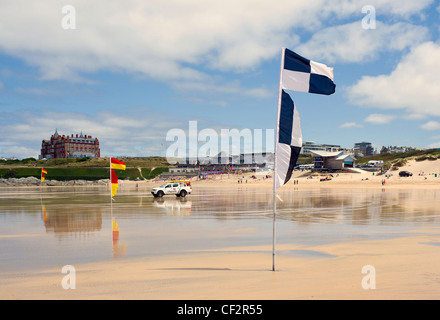 Ein Rettungsschwimmer Fahrzeug geparkt auf Fistral Beach zwischen roten und gelben Flaggen, die darauf hinweist, dass das Gebiet von Rettungsschwimmern, patrouillierten ist ein Stockfoto