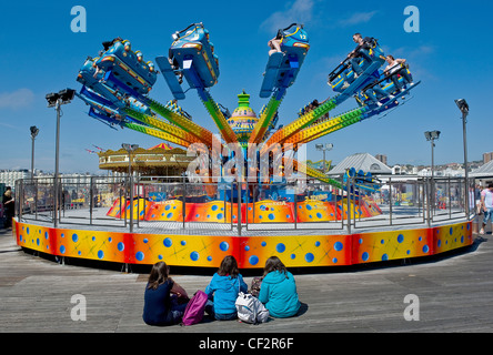 Drei junge Mädchen sitzt vor einem Messegelände fahren auf Brighton Pier. Stockfoto