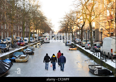 Die Menschen gehen auf zugefrorenen Kanälen im Zentrum von Amsterdam, Niederlande. Stockfoto