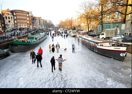 Die Menschen gehen auf zugefrorenen Kanälen im Zentrum von Amsterdam, Niederlande. Stockfoto