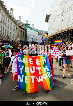 Mitglieder der Queer Youth Network paradieren mit einem bunten Regenbogen Banner stolz London feiern. Stockfoto