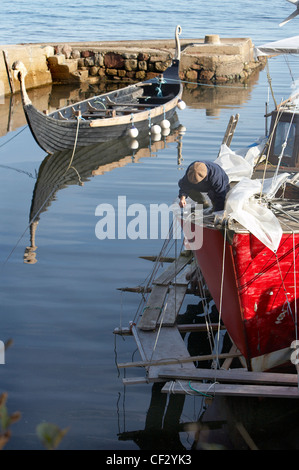 Ein Fischerboot in der Reparatur und Replik Wikingerboot im Hafen von Corrie auf der Isle of Arran. Stockfoto