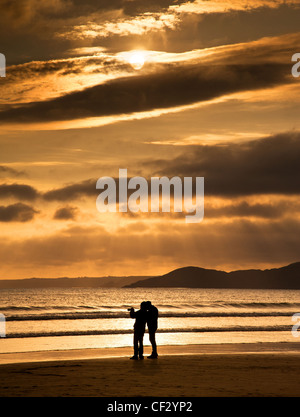 Fotograf auf Newgale Strand, Pembrokeshire, bei Sonnenuntergang. Stockfoto