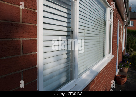 Weiß gerahmte Fenster mit weißen blind in Ziegelmauer an Vorderseite des Hauses in spitzen Winkel Stockfoto