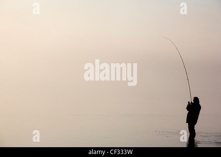 Die Silhouette der ein einsamer Angler Angeln im Bassenthwaite Lake im Lake District. Stockfoto