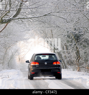 Winter Wetter Wunderland VW Volkswagen Golf Auto Fahren auf Schnee und Eis bedeckte Straße durch Torbogen von weißen Bäumen Essex England UK (verdeckte Zahl) Stockfoto