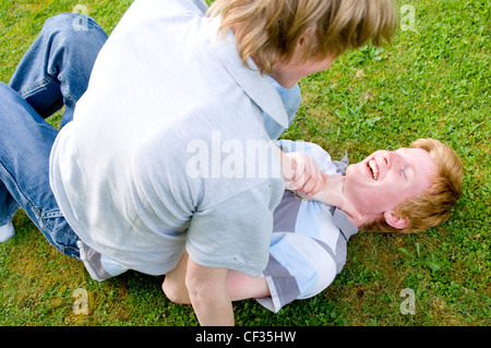 Zwei männliche Jugendliche spielen kämpfen im Garten Stockfoto