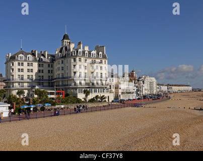 Menschen zu Fuß entlang der Promenade, vorbei an Hotels und Pensionen am Strand von Eastbourne. Stockfoto