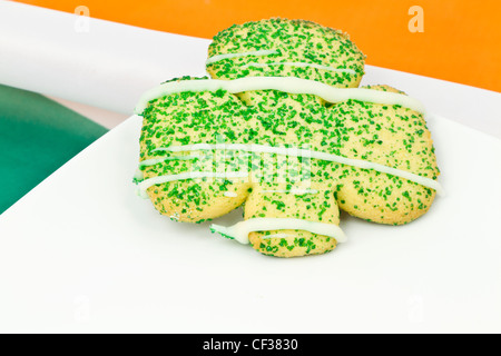 Cookie in Kleeblatt-Form auf weißen Teller auf die Farben der irischen Flagge gelegt. Stockfoto