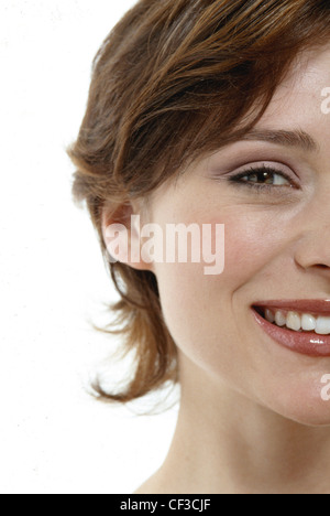 Weibliche brünette Haare, trägt rosa schimmernden Lidschatten, schwarzem Eyeliner, rosa Rouge und roten Lipgloss, lächelnd, mit Blick auf Stockfoto