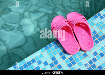 Strand-Pantoffeln auf Poolseite Stockfoto