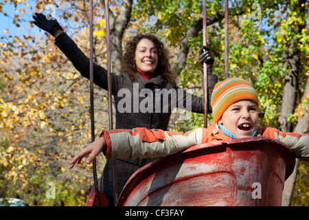 Mutter mit Sohn schütteln auf Schaukel im herbstlichen park Stockfoto