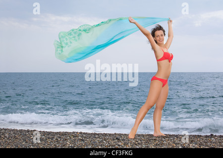 schöne junge Frau mit Stoff stehend auf steinigen Strand Stockfoto