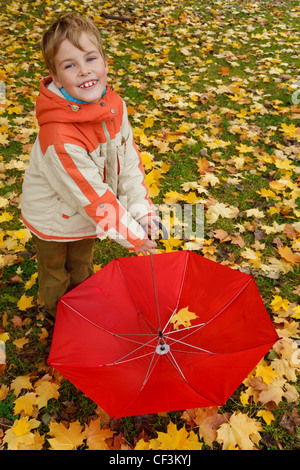 Porträt eines jungen im Herbst Park. Im abgesenkten Hand roten Regenschirm hält. Ansicht von oben. Stockfoto