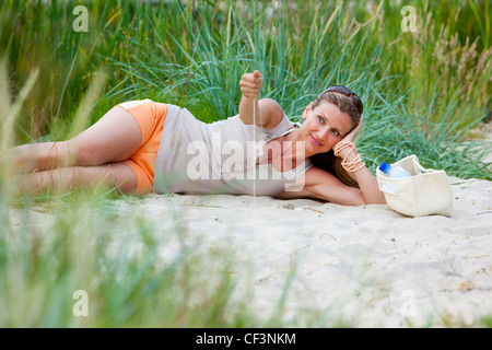 Lächelnde Frau, die am Strand liegen Stockfoto