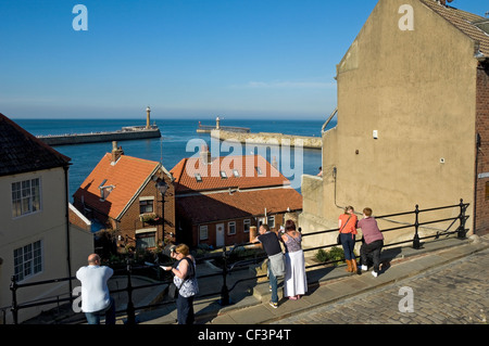 Menschen mit Blick auf den Hafen und die Pier Leuchttürme in Whitby. Stockfoto