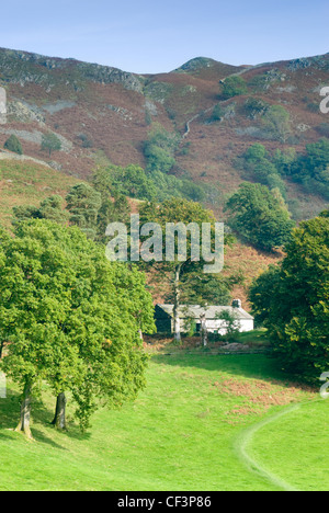 Ein traditionelles weiß gewaschen Haus befindet sich rund um Loughrigg Tarn mit einer Trockensteinmauer trennen die Felder hinaus. Stockfoto