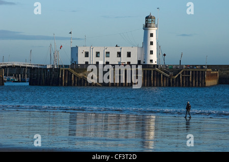 Eine einsame Person, zu Fuß entlang der Küste von Scarborough Leuchtturm auf Vincent Pier. Stockfoto