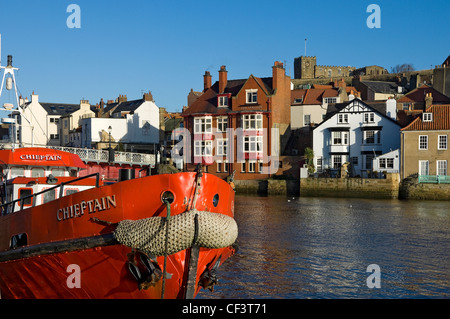 Ein Fischerboot vor Anker im Hafen von Whitby, von Str. Marys Kirche auf dem Hügel oben übersehen. Stockfoto