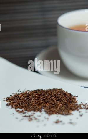 Nahaufnahme der Redbush lose Teeblätter mit einer Tasse Tee im Hintergrund. Stockfoto