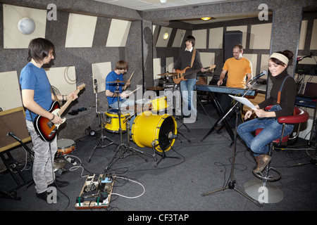 eine Rock-Band. Sänger Mädchen, zwei Musiker mit Elektro-Gitarren, Keyboarder und einen Schlagzeuger im Studio arbeiten Stockfoto