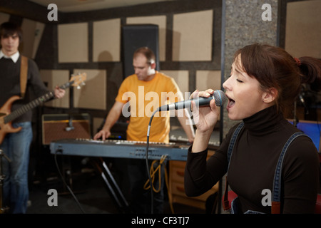 Sänger-Mädchen singt. Elektro-Gitarrist und Keyboarder in unscharf Stockfoto