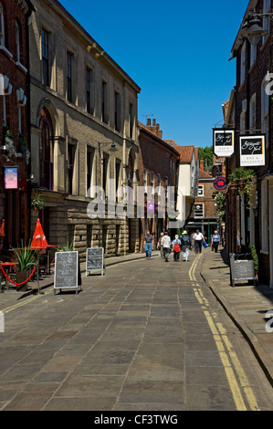 Touristen zu Fuß vorbei an Bars und Brasserien in Stonegate. Stockfoto