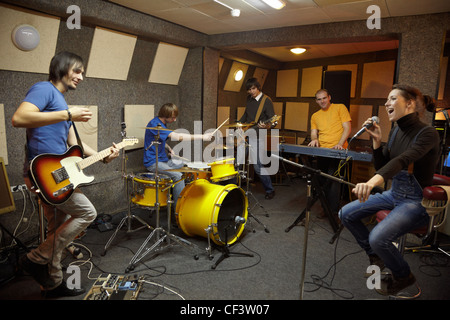 eine Rock-band Sänger Mädchen zwei Musiker Elektro Gitarren Keyboarder ein Schlagzeuger arbeiten im Studio Freude Schöpfung Stockfoto