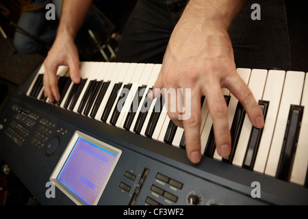 Hände der Keyboarder auf Tasten Synthesizer. große Finger der linken Hand im Fokus Stockfoto