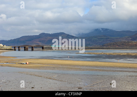 Ein Zug eine eingleisige Eisenbahnviadukt über die Mündung des Flusses Afon Mawddach Barmouth Brücke überqueren. Stockfoto