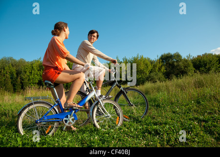 Das Mädchen und der Mann gehen für eine Fahrt auf dem Fahrrad an einem sonnigen Tag Stockfoto