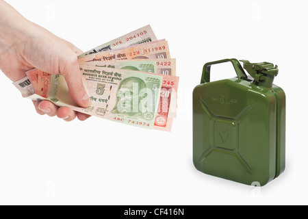 Viele verschiedene indische Rupie Rechnungen sind in der Hand gehalten. In der Nähe ist durch ein grünen 5 Liter Benzin Kanister Metall, Hintergrund weiß. Stockfoto