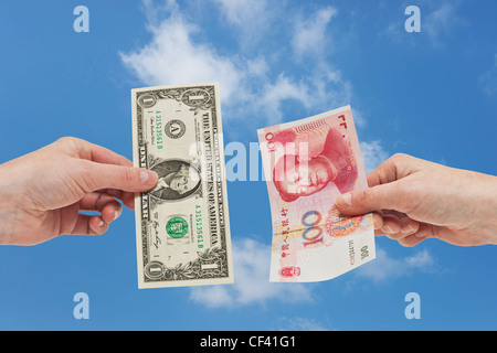 Ein 1 US-Dollar-Schein in der Hand gehalten wird. Auf der anderen Seite eine 100 Yuan Rechnung in der Hand, Hintergrund Himmel gehalten. Stockfoto