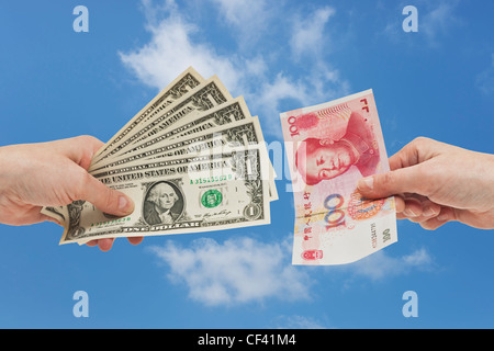 Fünf 1 US-Dollar-Scheine in der Hand gehalten werden. Auf der anderen Seite ist eine 100 Yuan Rechnung in der Hand, Hintergrund Himmel gehalten. Stockfoto