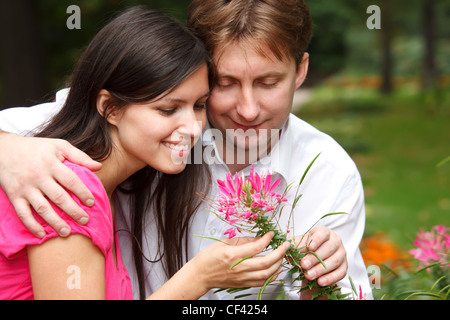 Mann und Mädchen im Sommergarten. Mann umarmt Girl zeigt es Blume. Hautnah. Stockfoto