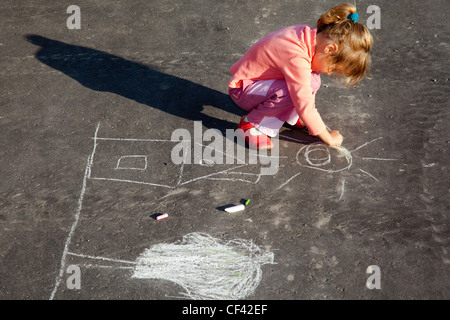 Mädchen sitzt auf Beton Asphalt Quadratmeter Straße Mädchen zieht Malerei Linie Kreide auf Asphalt Chld Zeichnungen Gemälde auf Asphaltbeton Stockfoto