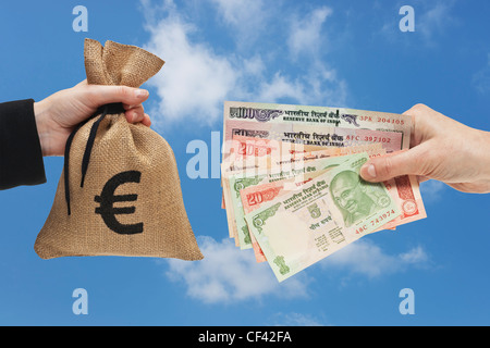 Viele verschiedene indische Rupie Rechnungen sind in der Hand gehalten. Auf der anderen Seite ein Geldsack mit Euro-Währung-Zeichen ist. Stockfoto