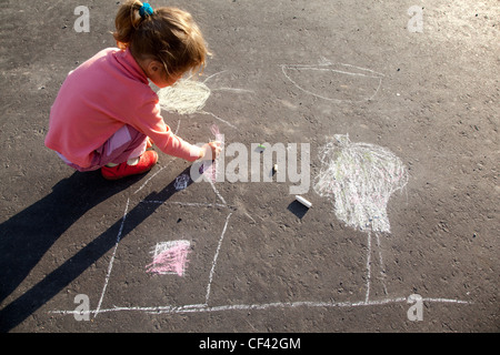 Mädchen sitzt Beton Asphalt Quadratmeter Straße Mädchen zieht Malerei Linie Sonne Haus Baum Asphalt Chld Kreidezeichnungen Gemälde asphalt Stockfoto