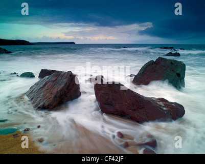 Wellen an den Strand um große Felsbrocken im Süßwasser West während der Flut. Stockfoto