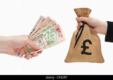 Viele verschiedene indische Rupie Rechnungen sind in der Hand gehalten. Auf der anderen Seite ein Geldbeutel mit Pfund-Währung-Zeichen in der Hand gehalten. Stockfoto