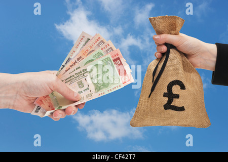 Viele verschiedene indische Rupie Rechnungen sind in der Hand gehalten. Auf der anderen Seite ein Geldbeutel mit Pfund-Währung-Zeichen in der Hand gehalten. Stockfoto