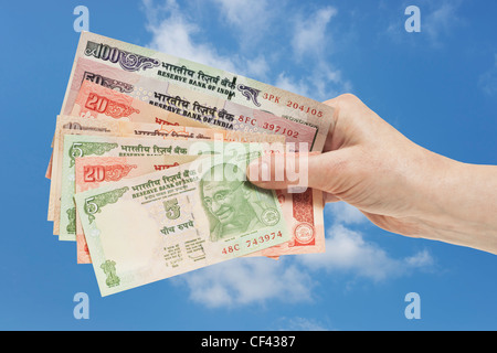 Viele verschiedene indische Rupie Rechnungen mit dem Porträt von Mahatma Gandhi sind in der Hand gehalten. Himmel ist im Hintergrund. Stockfoto