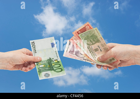 Viele verschiedene indische Rupie Rechnungen sind in der Hand gehalten. Auf der anderen Seite ist ein 100 Euro-Schein in der Hand, Hintergrund Himmel gehalten. Stockfoto