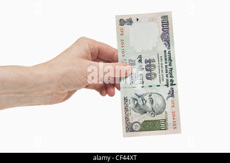Eine indische 100 Rupien Rechnung mit dem Porträt von Mahatma Gandhi ist in der Hand, weißen Hintergrund gehalten. Stockfoto