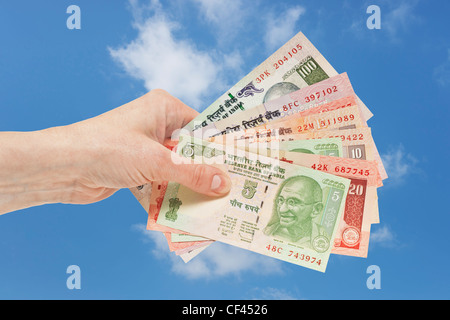 Viele verschiedene indische Rupie Rechnungen mit dem Porträt von Mahatma Gandhi sind in der Hand gehalten. Himmel ist im Hintergrund. Stockfoto